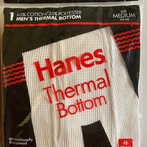 Peut inclure: Emballage de sous-v&ecirc;tements thermiques blancs avec du texte rouge et noir qui indique "Hanes Thermal Bottom" et "65% Coton/35% Polyester". L'emballage comprend &eacute;galement la taille "Medium (34-36)" et le texte "Garantie inconditionnelle".