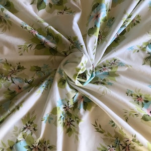 Puede incluir: Tela blanca con un patr&oacute;n floral con flores azules y rosas y hojas verdes.