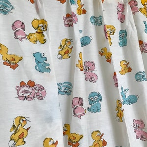 May include: White fabric with a repeating pattern of cartoon animals. The animals include ducks, kittens, puppies, and bunnies. The animals are in shades of yellow, blue, pink, and brown.