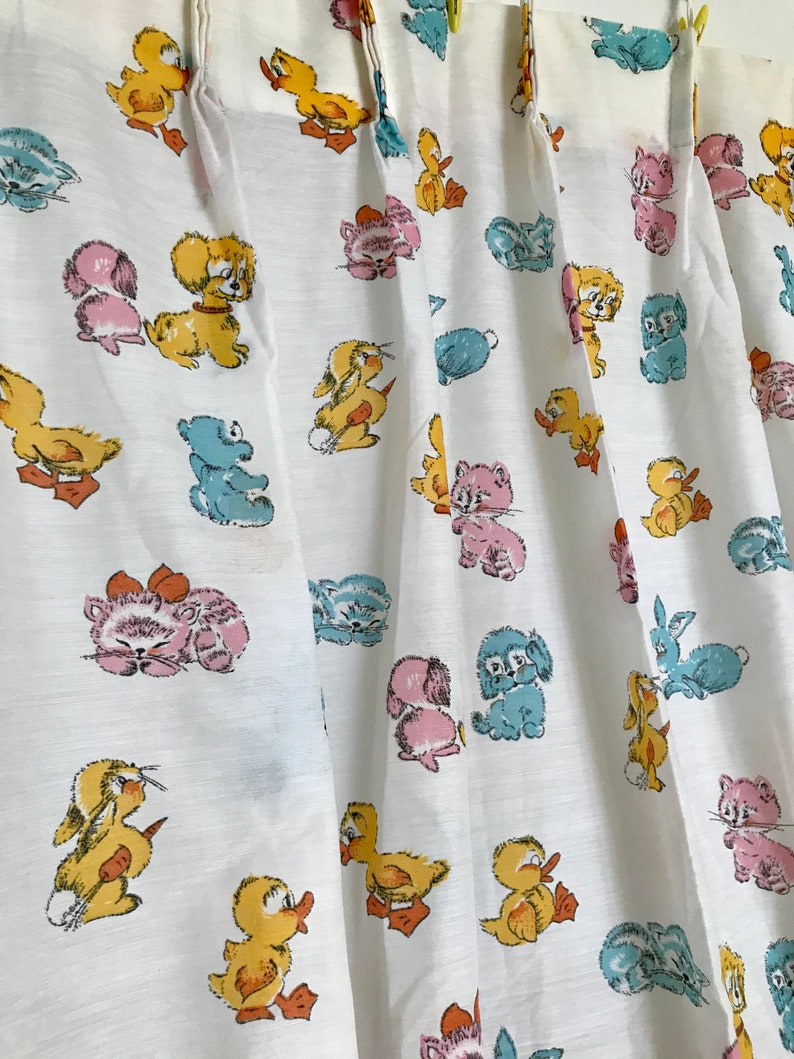 May include: White fabric with a repeating pattern of cartoon animals. The animals include ducks, kittens, puppies, and bunnies. The animals are in shades of yellow, blue, pink, and brown.