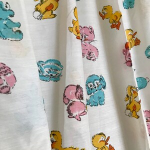 May include: White fabric with a repeating pattern of cartoon animals. The animals include a duck, a bunny, a cat, and a dog. The animals are all in different colors, including blue, yellow, pink, and orange.