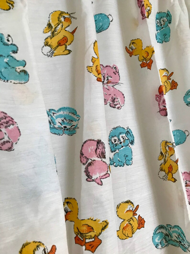 May include: White fabric with a repeating pattern of cartoon animals. The animals include a duck, a bunny, a cat, and a dog. The animals are all in different colors, including blue, yellow, pink, and orange.