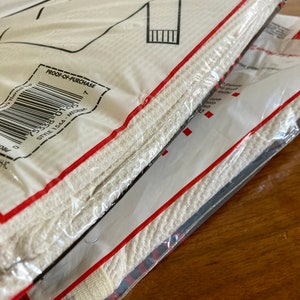 Peut inclure: Sous-v&ecirc;tements thermiques blancs emball&eacute;s dans un sac en plastique transparent avec une &eacute;tiquette rouge et blanche. L'&eacute;tiquette indique "Preuve d'achat" et comporte un code-barres. L'&eacute;tiquette indique &eacute;galement "Style 1544 - Medium".