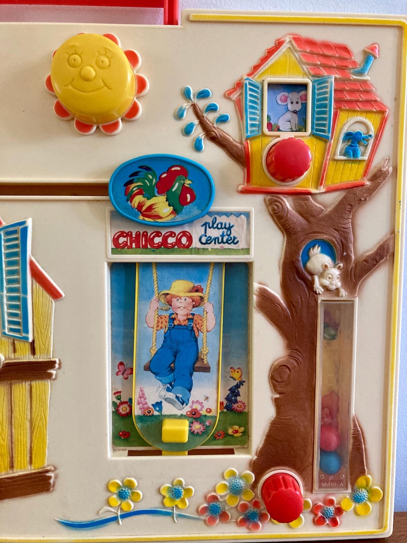 Puede incluir: Juguete vintage Chicco Play Center con un sol amarillo, un emblema de gallo y un ni&ntilde;o en un columpio. El juguete presenta una casa con un rat&oacute;n, un &aacute;rbol con un conejo y botones coloridos. El juguete es de pl&aacute;stico.