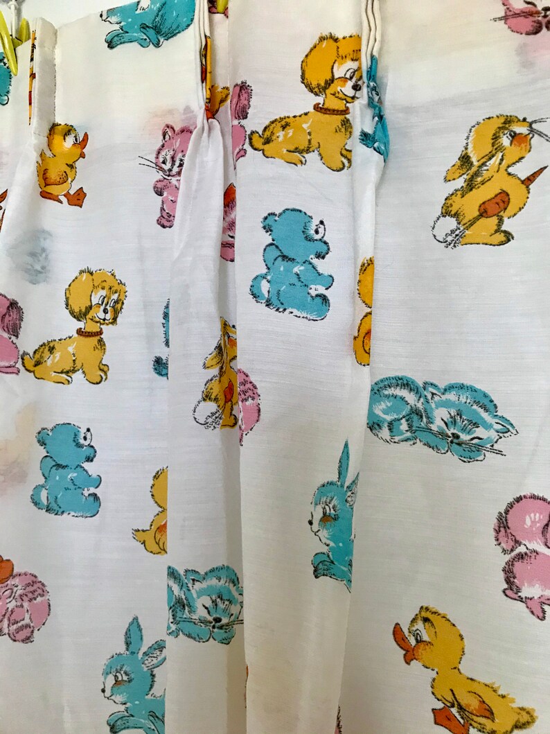 May include: White fabric with a repeating pattern of cartoon animals, including a duck, cat, dog, bear, rabbit, and bunny. The animals are in various colors, including yellow, blue, pink, and brown.