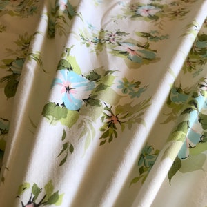 Puede incluir: Tela blanca con un patr&oacute;n floral con flores de color azul claro y rosa con hojas verdes.