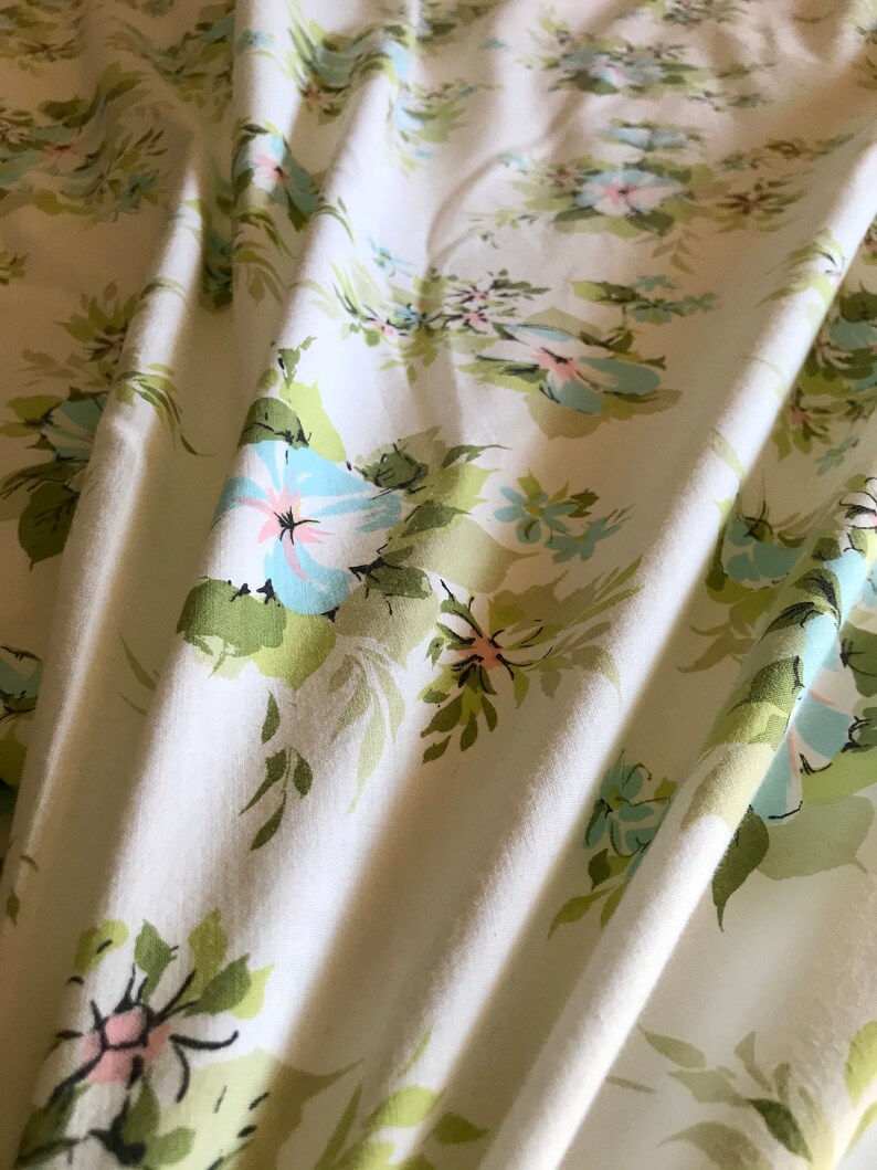 Puede incluir: Tela blanca con un patr&oacute;n floral con flores de color azul claro y rosa con hojas verdes.
