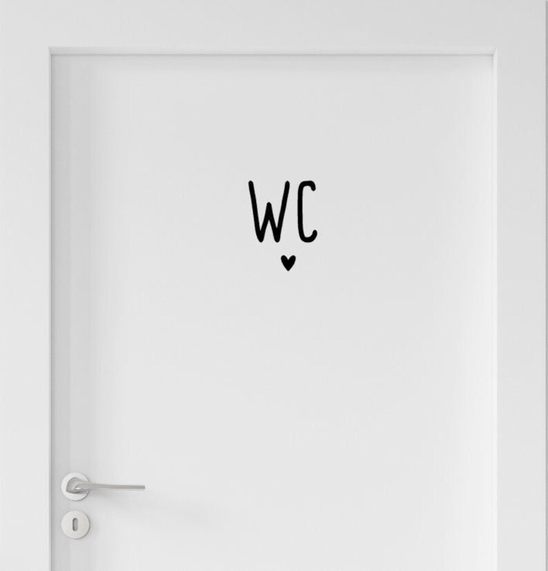 Peut inclure: Une porte blanche orn&eacute;e d'un autocollant en vinyle noir affichant les lettres WC dans une police manuscrite, plac&eacute;es au-dessus d'une petite ic&ocirc;ne de c&oelig;ur noir plein. La porte comporte une poign&eacute;e en m&eacute;tal argent&eacute; et une plaque de serrure assortie.