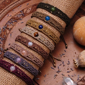 May include: A collection of eight handmade friendship bracelets with different colored cords and gemstone beads. The bracelets are arranged on a brown burlap background.