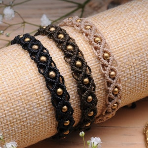 May include: Three braided bracelets with gold beads. The bracelets are black, brown, and beige.
