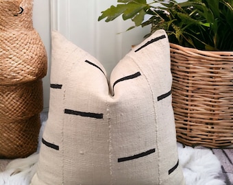 May include: A white throw pillow with black geometric lines. The pillow is made of a textured fabric and has a simple, modern design.