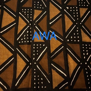May include: A black and brown fabric with a geometric pattern of triangles and white lines. The fabric has the word "AWA" printed in blue letters in the center.