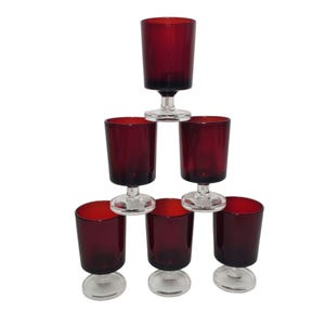 Peut inclure: Ensemble de six verres à vin en verre rouge avec des tiges claires. Les verres sont empilés en forme de pyramide.