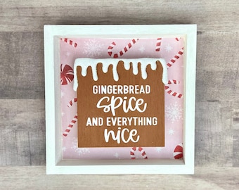Könnte beinhalten: Ein weiß gerahmtes Schild mit rosa Hintergrund, das ein Lebkuchenhaus mit dem Text "Gingerbread Spice and Everything Nice" zeigt.