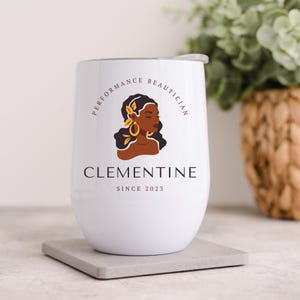 May include: White stainless steel wine tumbler with a logo that says "Performance Beautician Clementine Since 2023". The logo features a stylized illustration of a woman with brown skin and a floral design in her hair.
