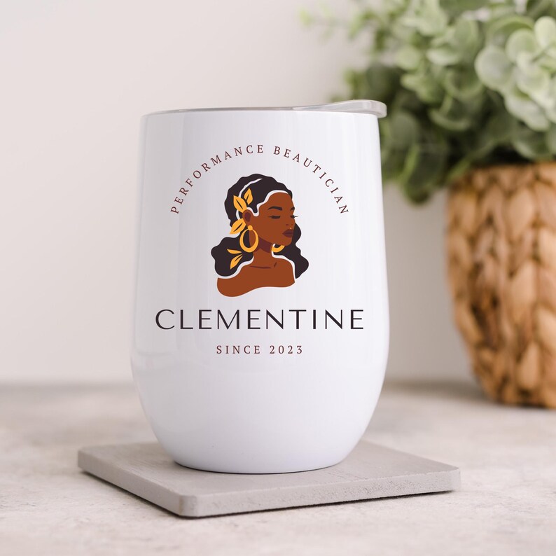 May include: White stainless steel wine tumbler with a logo that says "Performance Beautician Clementine Since 2023". The logo features a stylized illustration of a woman with brown skin and a floral design in her hair.