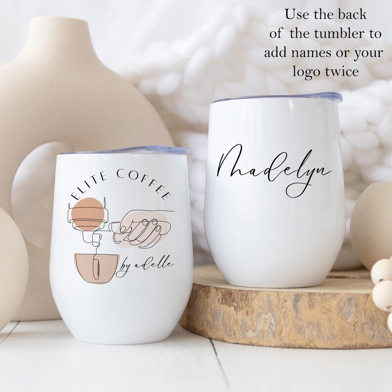 May include: Two white stainless steel tumblers with lids. One tumbler has the text "ELITE COFFEE by abelle" and a line drawing of a coffee maker. The other tumbler has the name "Madelyn" written in cursive.