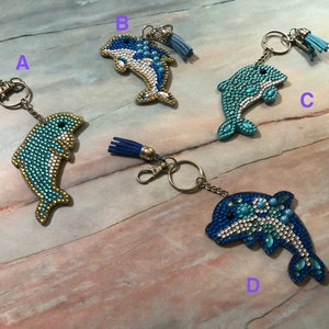 May include: Four dolphin keyrings with blue and white rhinestones. Each keyring has a different design and a tassel.