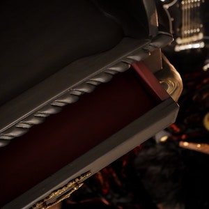 May include: A black dresser with a drawer open, revealing a red interior. The drawer has a rope-like design on the front edge. The dresser is in a dark room with a guitar and a candle in the background.