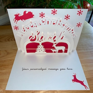 Tarjeta de Navidad desplegable 3D personalizada con reno y árbol de Navidad. Haz que la Navidad de alguien sea memorable con esta tarjeta personalizada.