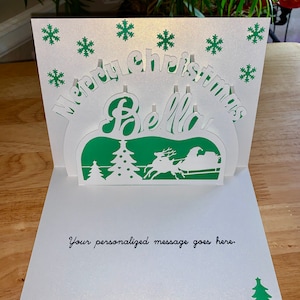 Gepersonaliseerde 3D pop-up kerstkaart met kerstman op slee en kerstboom. Maak iemands kerst onvergetelijk met deze gepersonaliseerde kaart.
