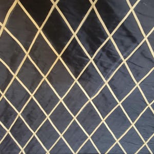 May include: Dark navy fabric with a diamond pattern created by light beige lines. The lines form a grid of diamond shapes across the surface of the fabric. The fabric has a slight sheen.