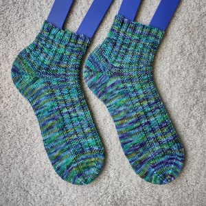 May include: A pair of blue and green striped socks with a ribbed texture, displayed on blue sock blockers.