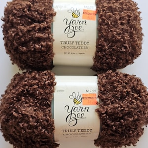 May include: Two skeins of Yarn Bee Truly Teddy Chocolate BR yarn. The yarn is a rich brown color with a textured, looped appearance. Each skein has a label with the Yarn Bee logo and product information.