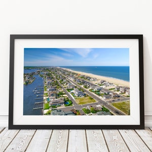 Puede incluir: Vista aérea de una ciudad costera con casas, calles y una playa. El agua es azul y el cielo está despejado.