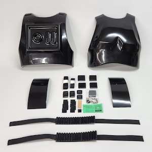 Op de afbeelding: Een zwarte plastic kostuumset voor een Stormtrooper, bestaande uit twee borststukken, twee schouderstukken, twee banden en een verscheidenheid aan hardware en bevestigingsmiddelen.