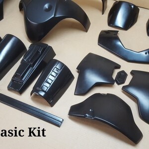 Pode incluir: Um kit de pl&aacute;stico preto para um fato de Star Wars. O kit inclui pe&ccedil;as para o peito, os ombros, os bra&ccedil;os e as pernas. O kit &eacute; etiquetado como "ROTJ Basic Kit".