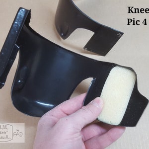 May include: Close-up of a black knee pad with a foam insert. The knee pad is designed to protect the knee from impact and abrasion. The foam insert is designed to provide cushioning and comfort. The knee pad is part of a knee kit.
