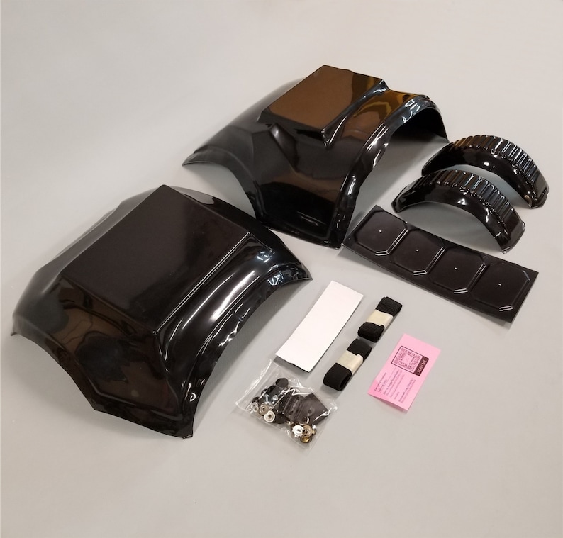 Puede incluir: Un conjunto de piezas de carrocer&iacute;a de coche de pl&aacute;stico negro para un coche modelo. El conjunto incluye dos paneles de carrocer&iacute;a grandes, dos pasos de rueda m&aacute;s peque&ntilde;os, una pieza plana con cuatro agujeros y una peque&ntilde;a bolsa de sujetadores. El conjunto tambi&eacute;n incluye dos correas negras y una hoja de instrucciones rosa.