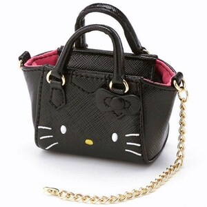 May include: A black handbag with a gold chain and two small handles. The bag features a Hello Kitty design with white whiskers, white eyes, and a yellow nose. The interior is pink.