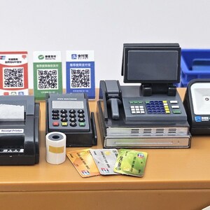 May include: A miniature cash register set with a receipt printer, POS machine, scanner, and credit cards. The set includes a cash register with a screen, a scanner, and several payment options.
