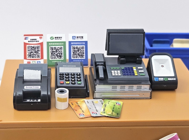 May include: A miniature cash register set with a receipt printer, POS machine, scanner, and credit cards. The set includes a cash register with a screen, a scanner, and several payment options.