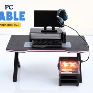 May include: A black computer desk with a pink edge, a black monitor, a black keyboard, a black headset, and a black computer tower. The desk is labelled "PC TABLE MINIATURE SIZE".