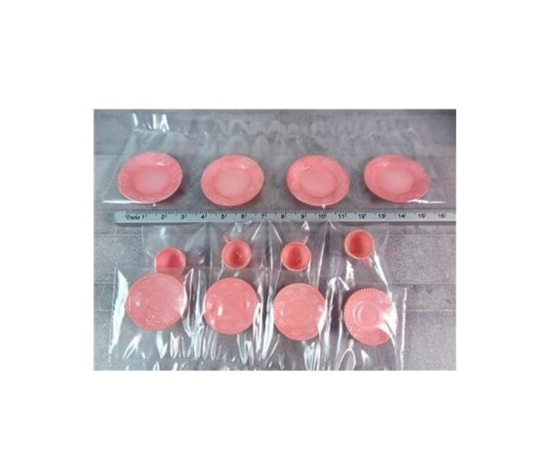 May include: A set of pink plastic teacups and saucers. The set includes four teacups and four saucers, all in a pale pink color. The teacups and saucers are decorated with a simple, elegant design.