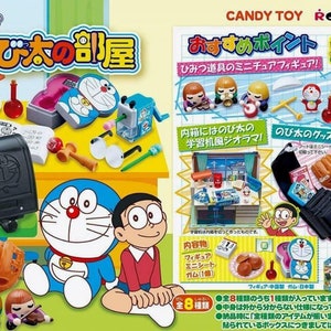 May include: A set of eight miniature plastic figures of Doraemon and his friends from the Japanese manga series Doraemon. The figures are posed in various scenes from the show, including Doraemon sitting on a desk, Nobita sitting on the floor, and Shizuka playing the violin. The figures are all brightly colored and have a cartoonish style.