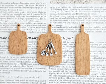 Puede incluir: Tres tablas de cortar de madera de diferentes tamaños con un acabado de vetas de madera natural. La tabla central tiene un juego de cucharas medidoras plateadas colgando. Las tablas se muestran sobre un fondo de papel impreso.