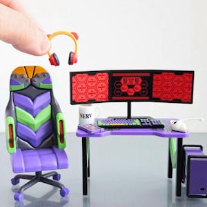 May include: Miniature gaming setup featuring a purple desk, chair, and computer tower. The desk has a keyboard, mouse, and triple monitor display. A pair of yellow and red headphones are held above the desk. The chair is purple, green, and gray.