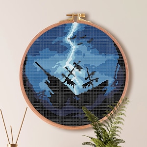 May include: A cross-stitch pattern of a ship sinking in a stormy sea with lightning striking the mast. The pattern is framed in a round wooden hoop and is 7.1 inches by 7.1 inches.