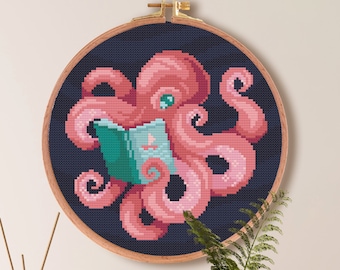 May include: A cross-stitch embroidery of a pink octopus reading a teal book, set against a dark blue background. The artwork is framed in a wooden hoop. The text on the image says "Size For Aida (14)" and "Color Palette".