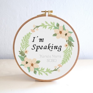 Op de afbeelding: Een witte borduurring met een bloemenkransontwerp en de tekst "I'm Speaking Kamala Harris 2020".