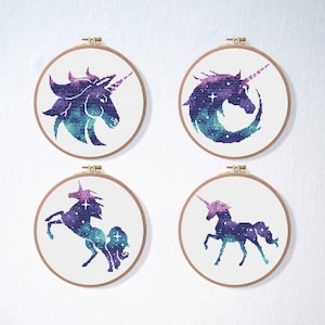 Puede incluir: Cuatro aros de bordado con diseños de punto de cruz de un unicornio de galaxia en diferentes poses. El unicornio es una silueta con un patrón de galaxia morado, azul y verde.