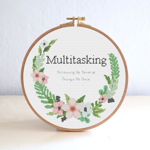 May include: A white embroidery hoop with a floral wreath design and the text "Multitasking Screwing Up Several Things At Once".