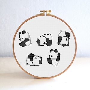 May include: A white embroidery hoop with black and white pixelated panda bears in different poses.