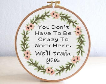 Puede incluir: Aro bordado con una corona de flores y el texto "You Don't Have To Be Crazy To Work Here. We'll Train You."