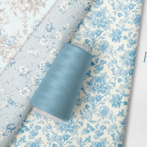 May include: A collection of floral toile seamless patterns in shades of blue and beige. A spool of blue thread sits atop the fabric. The text "Floral Toile" and "Seamless Patterns" is visible.