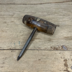 May include: A vintage wooden handled awl with a metal shaft and a pointed tip. The handle is brown and has a worn finish.
